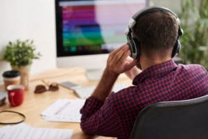 Rear view of sound engineer listening to new music track on computer