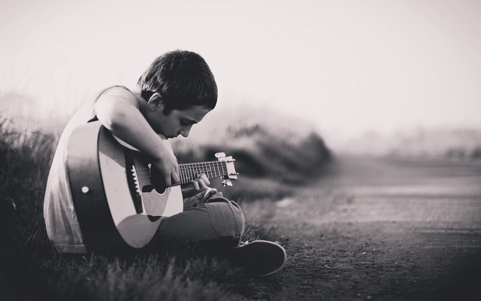 boy playing guitar alone on the road