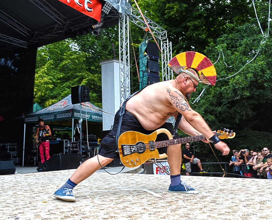 man playing his guitar in a festival as stress reliever
