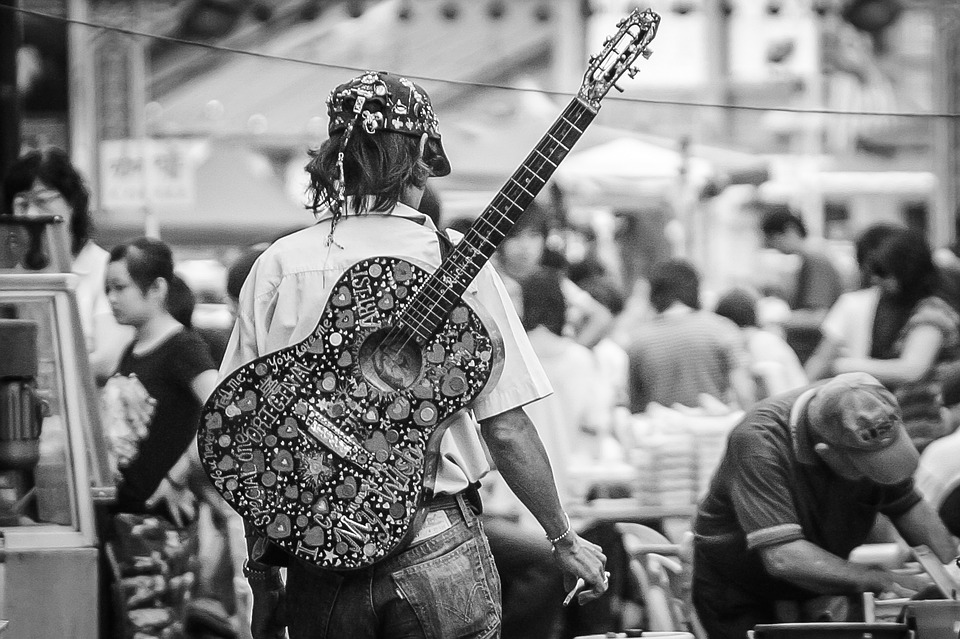 man carrying his guitar on his back for a walk