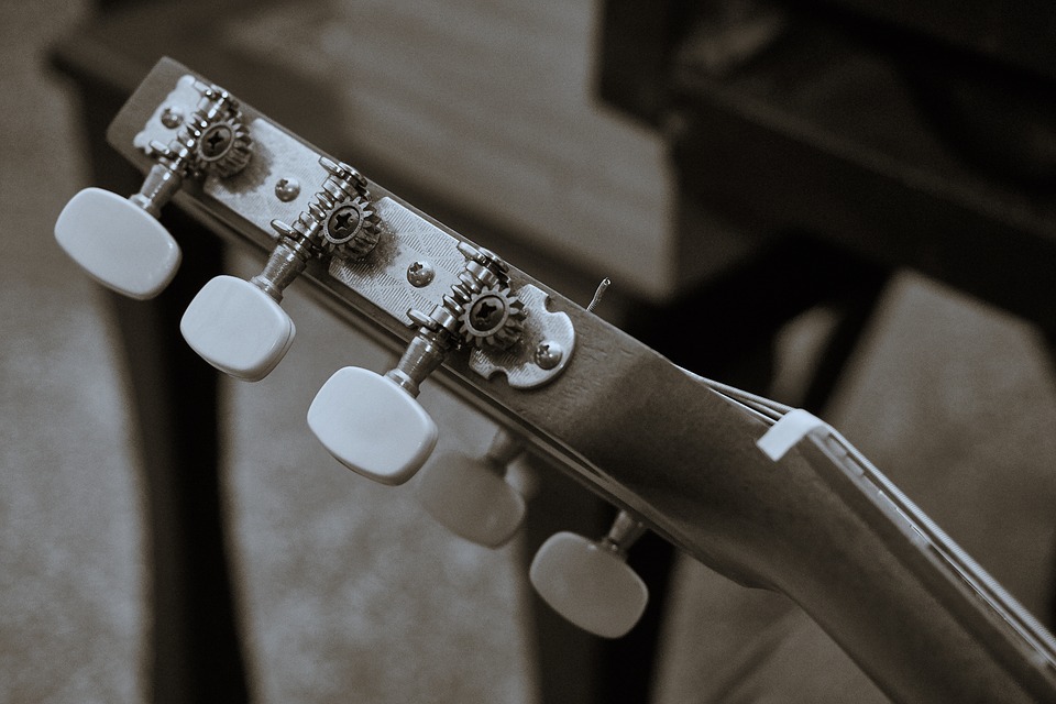 tuning the pegs or keys of the guitar