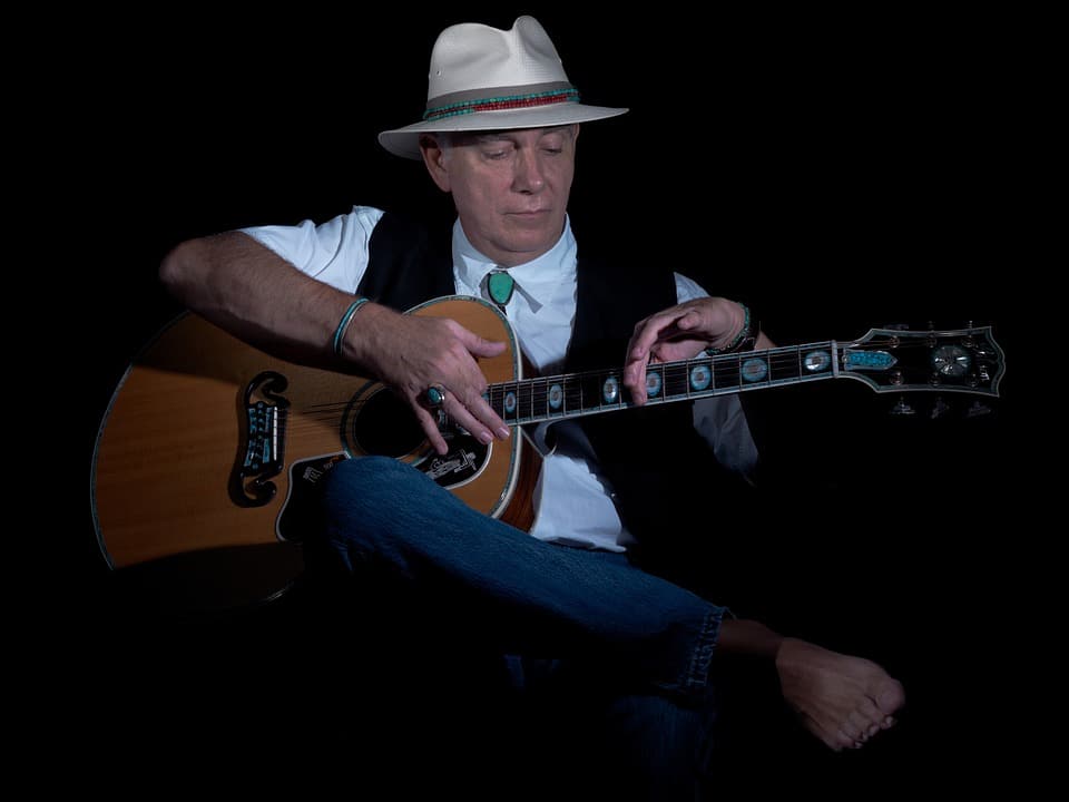 old man relaxes by playing his guitar