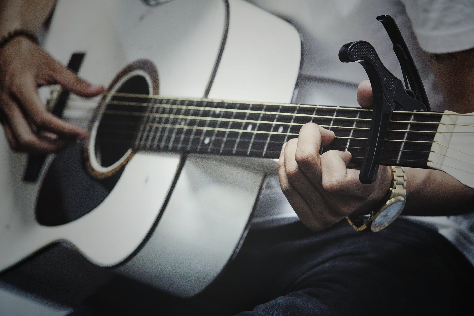 man playing a guitar using a capo