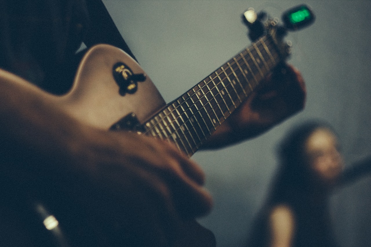 Man with electric guitar tuner at one end
