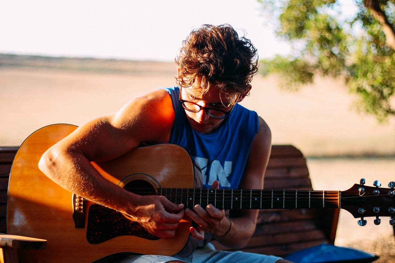 boy practicing his guitar lessons outdoor